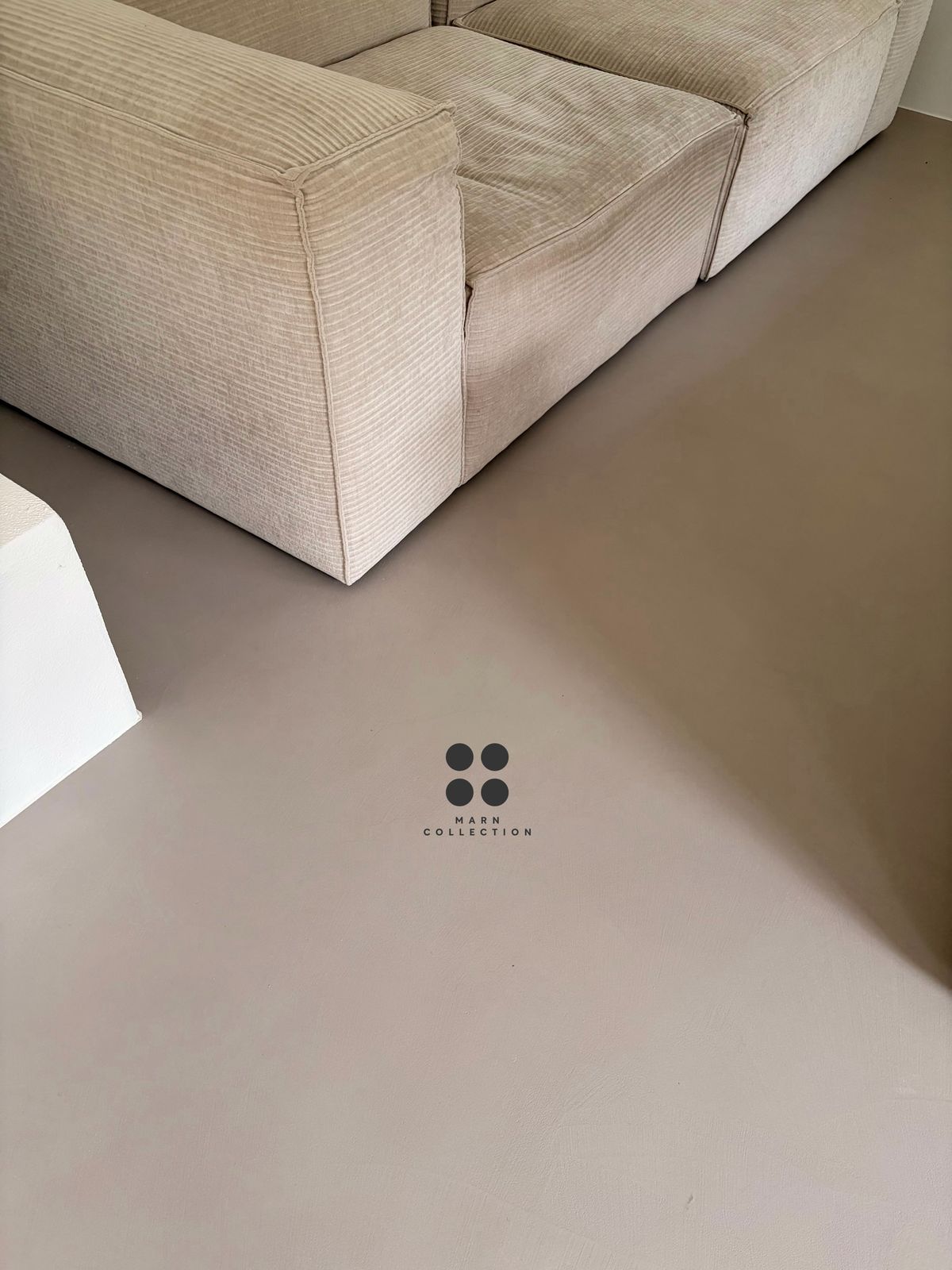 Wohnraum mit hellem fugenlosem Boden und Bouclé-Sofa